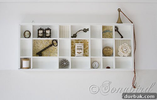 A curated display on a shelf, showing a collection of books, a small plant, and a framed photograph, all contributing to a minimalist aesthetic.