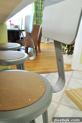 A view across the kitchen and into an adjoining dining room, emphasizing the visual harmony created by the metal stools.