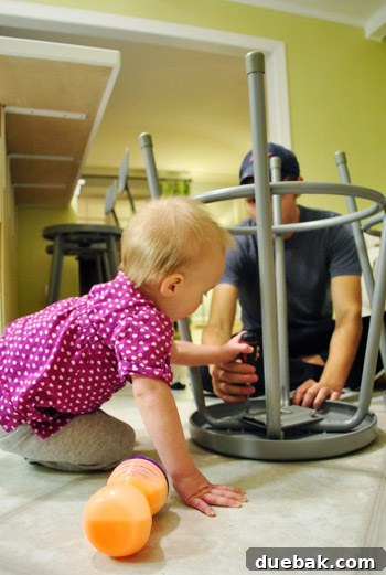 A young child (Clara) helping to assemble one of the industrial metal stools on the floor.