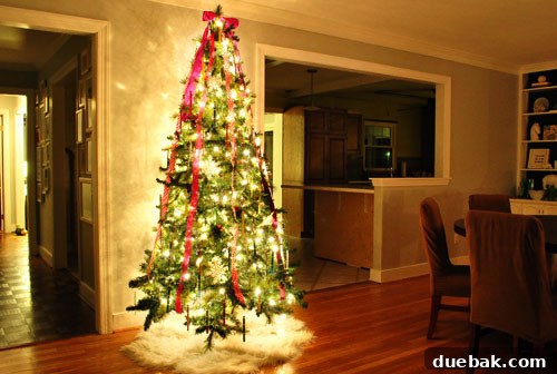 Christmas tree base with ribbon decorations and faux sheepskin skirt.