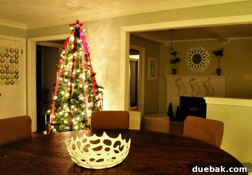 View of a decorated living space with a Christmas tree and mantel.