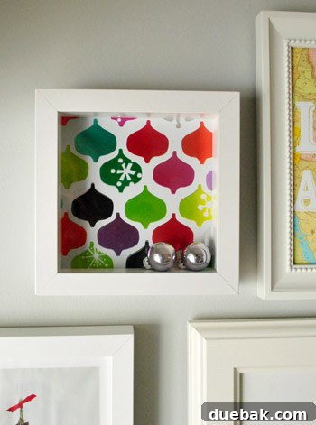 Close-up of silver ornaments within a shadow box with wrapping paper background.