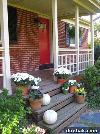 Final porch decor with cream-white pumpkins, flowers in pots.