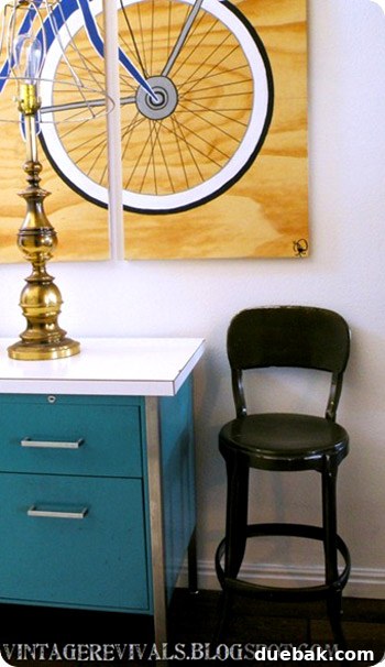 Close-up of entryway decor including books, lamp, and a small stool