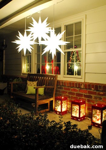 Our Dazzling Outdoor Christmas Display 11 Three Moravian stars hanging at varying heights from the scalloped header of the porch, creating a magical celestial display.