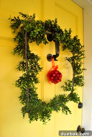 Our Dazzling Outdoor Christmas Display 15 The unique DIY square wreath made from four sticks gathered from the yard, adorned with a faux boxwood garland, hanging on the front door.