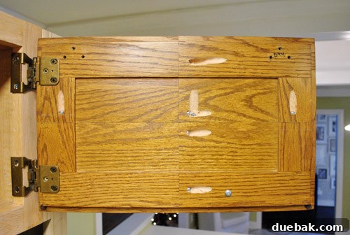 Rear view of a refitted cabinet door, showing screw holes to be filled with wood putty.