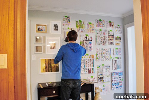 A long hallway wall adorned with a large, elaborate frame collage, featuring various sizes and styles of frames.
