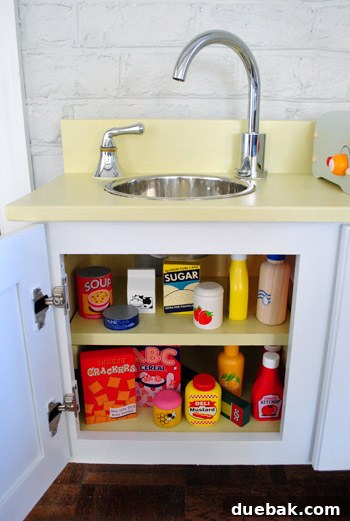 Play kitchen cabinet with added interior shelf for play food storage