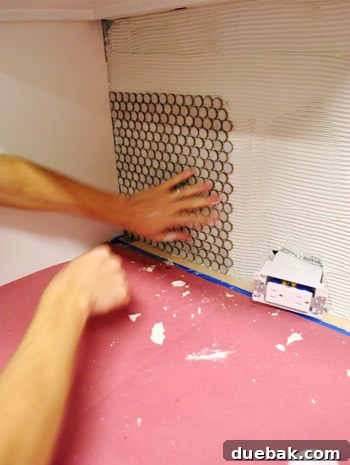First penny tile sheet being pressed onto the wall