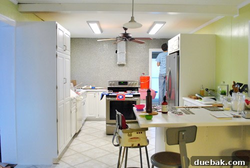 Kitchen corner with the oven pulled out, showing the final stages of tile installation