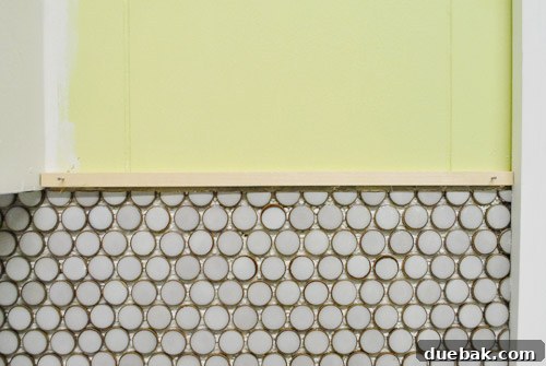 Kitchen wall with penny tiles and temporary wood trim, illustrating the final trim plan