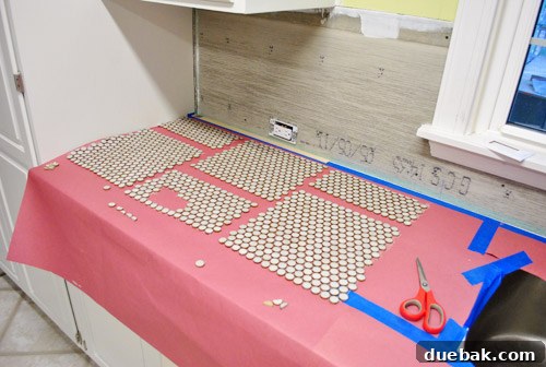 Close-up of penny tile sheets being carefully aligned in a staggered pattern