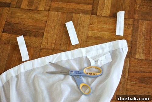 Repurposing Curtain Panels 5 Person meticulously cutting off tab tops from white sheer curtains.