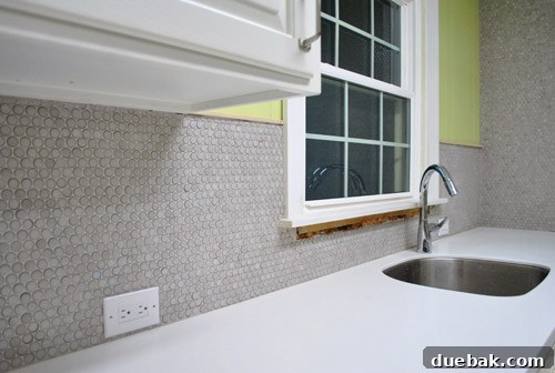 Close-up of penny tiles showing varying tones and a polished shine on some tiles.