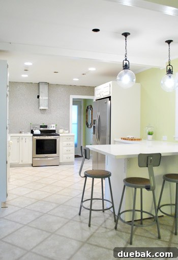 Elevating Kitchen Style with Twin Glass Pendants 4 A tall shot showing a kitchen peninsula with two pendant lights, a sink, and a white countertop