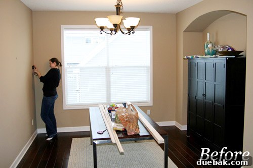Before shot of a dining room with only a table and bamboo armoire, symbolizing a blank canvas awaiting a DIY makeover. The room appears sparse and lacks character, setting the stage for a dramatic transformation.