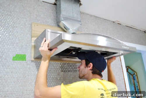 Homeowner installing range hood with partner's assistance