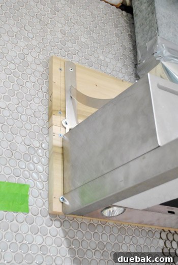 Homeowner attaching the first metal bracket to range hood