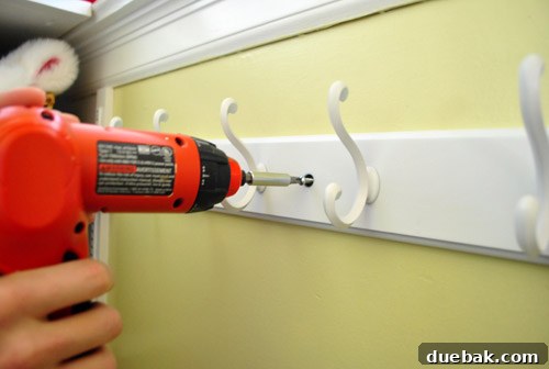 Streamline Your Laundry and Mudroom 4 White coat rack securely mounted on a white wall in a laundry room.
