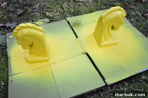 DIY Bookends: A Burst of Color 5 The ceramic horse heads being spray painted with a bright yellow color, showing the process of applying the new coat.