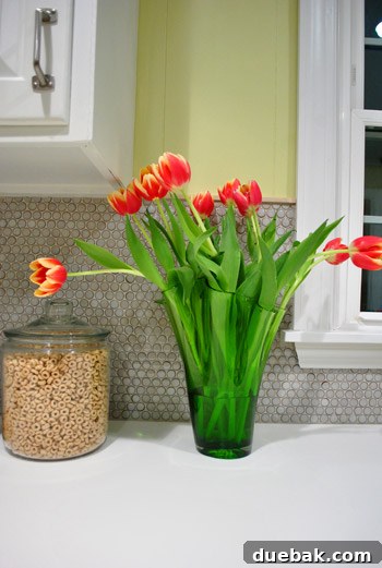 Elegant white vase with floppy two-tone tulips on a kitchen counter, bringing a touch of nature indoors amidst home renovation.