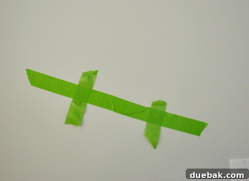 The painter's tape template left on the wall after removing the goose art, showing pre-poked nail holes.