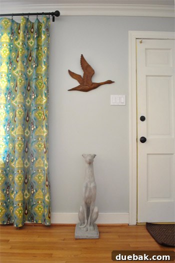 The vintage metal goose wall hanging displayed on a wall in the dining room, above a concrete greyhound statue.