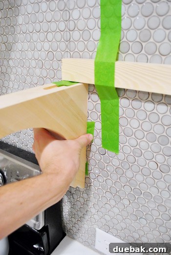 The paper template remaining on the tiled wall after the bracket has been carefully removed.