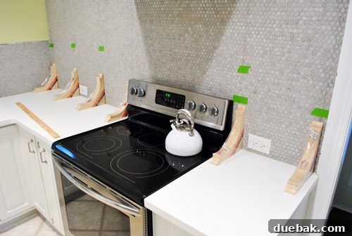 Kitchen wall with marked stud locations using hanging threads, indicating bracket placement.