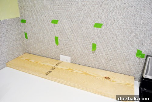 Cut wooden shelf boards lying on the floor, with subtle hanging threads visible against the tiled wall.