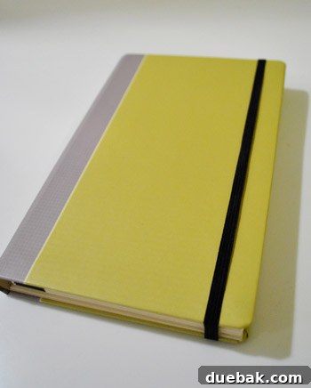 A person holding a slim, beige organizer with a notepad and accordion pockets, showcasing its compact design.