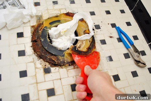 Rock-Solid Toilet: Easy DIY Fix 13 Scraping away old toilet wax ring with putty knife