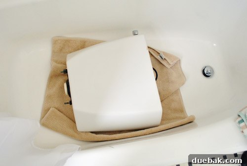 Rock-Solid Toilet: Easy DIY Fix 8 Toilet tank resting safely on soft towel in tub during repair