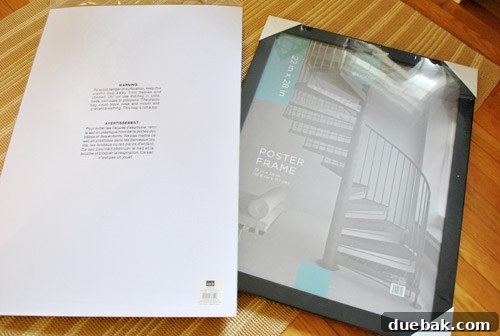 The essential tools and materials for an affordable DIY art framing project: a sleek black frame, a pristine sheet of archival mat board, and a can of white spray paint, ready for transformation.