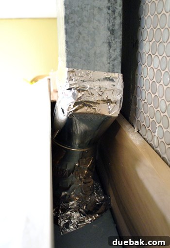 Applying metal foil tape to seal a kitchen range hood vent for proper ventilation