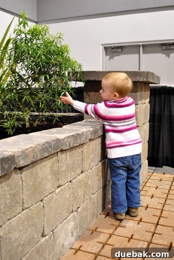 Clara playing landscaper amidst a lush garden display at the Home & Garden Show