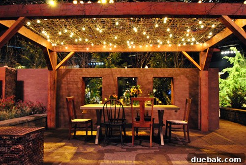 Inviting outdoor dining setup created indoors with string lights, pergolas, and mismatched chairs