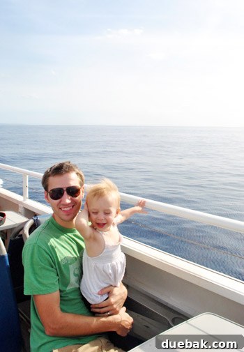 A family on a whale watching boat, with the child looking out at the ocean, ready for adventure.