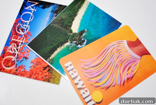A collection of colorful postcards, featuring various Hawaiian scenes, laid out on a table.
