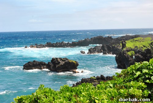 A stunning sea arch formation at Waianapanapa State Park, with waves crashing against the rugged black coastline.