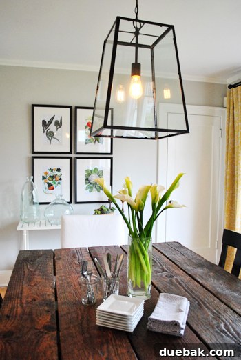 Dining room featuring a reclaimed wood table with historical significance, elegant black-framed artwork, and Olympic Quill paint