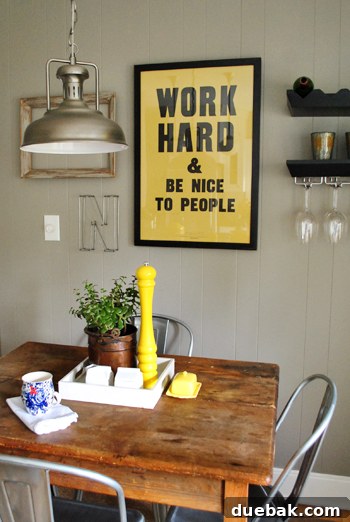 Charming kitchen eat-in area with a vibrant yellow poster as a focal point and a stylish yellow Anthropologie peppermill