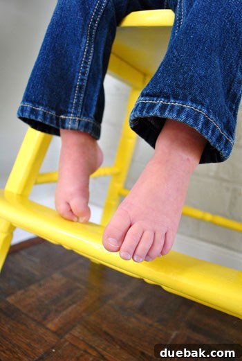 Giving an Old Wooden Highchair a Makeover 16 toddler's hand on yellow highchair