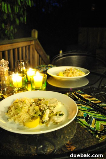 A romantic outdoor dinner setting with candles and food on a patio