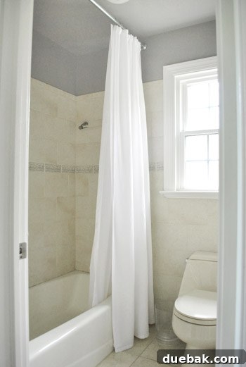 Bathroom with new paint, showing white shower curtain and existing tan/gray tones.