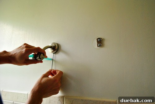Wall after removing shelf and towel bar, revealing initial damage.