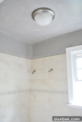 First coat of semi-gloss Rockport Gray paint applied to bathroom wall.