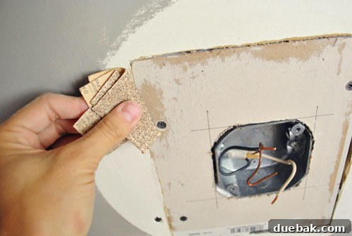 Upgrade Your Boob Light to a Modern Pendant 12 Sanding the edges of the newly installed drywall patch on the ceiling.