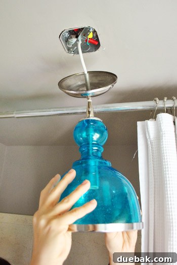 Upgrade Your Boob Light to a Modern Pendant 20 Sherry holding the light fixture while electrical connections are being made.